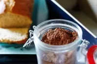 Kuchenform mit Kakaopulver ausstreuen