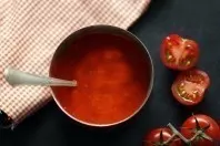 Die Tomaten, der Löffel und die Stoffserviette peppen das Foto der eher einfarbigen Tomatensuppe stark auf.