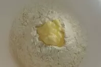 Mehl und Salz in eine Schüssel geben und eine Mulde hineindrücken, zerlassene Butter oder Öl hineingießen. 