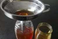 Honig aus dem Glas in vorhandene leere Flotte Biene umfüllen
